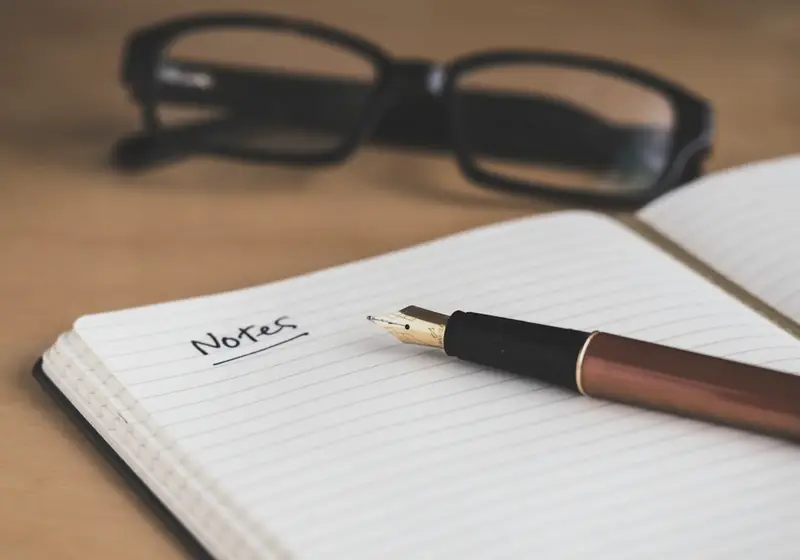 Libreta de notas con pluma y lentes