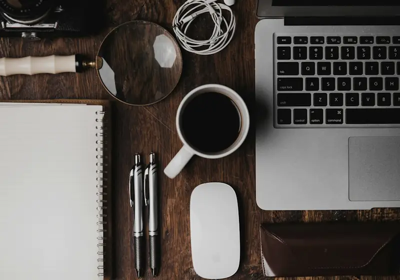 Escritorio de madera con laptop, café y libreta vista desde arriba