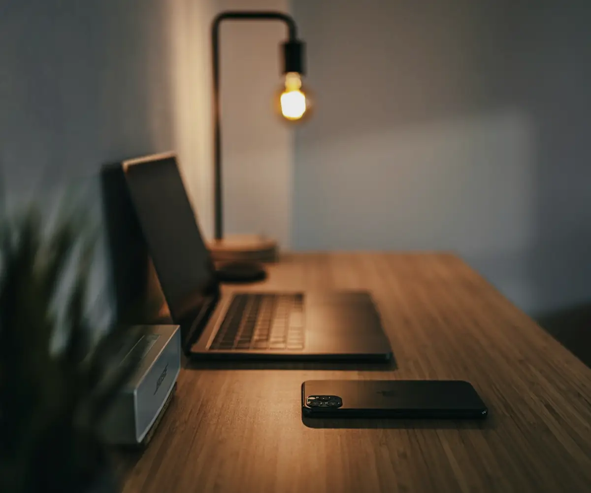 Escritorio de trabajo con laptop y lámpara en un ambiente sobrio